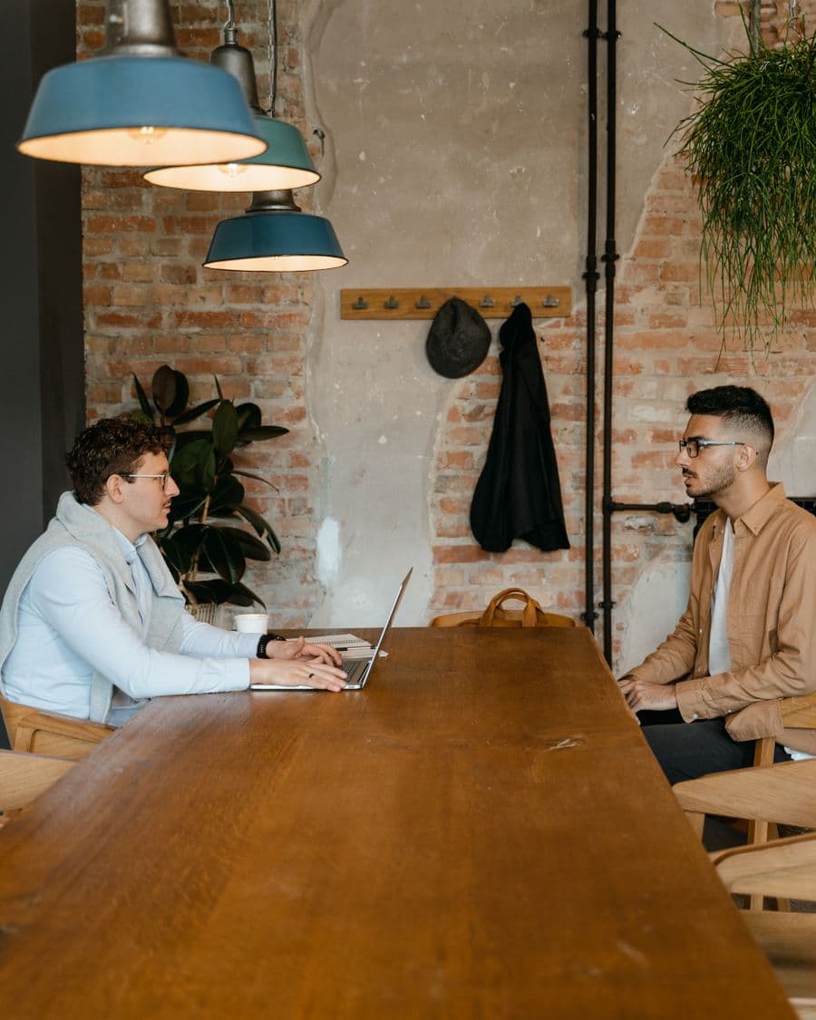 Twee mensen in gesprek aan een tafel tijdens een interview.